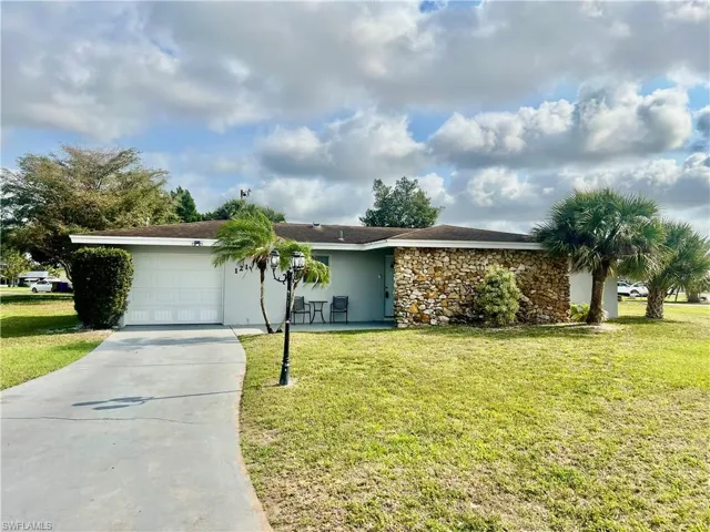 Ranch-style house featuring a garage and a front lawn
