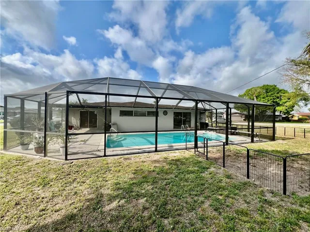 View of swimming pool with a lawn, a patio, and screen enclosure