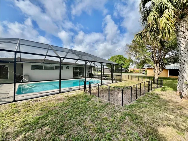 View of swimming pool featuring screen enclosure and a lawn