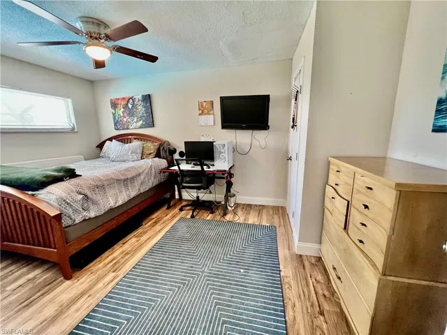 Bedroom featuring ceiling fan, light hardwood / wood-style flooring, and a textured ceiling