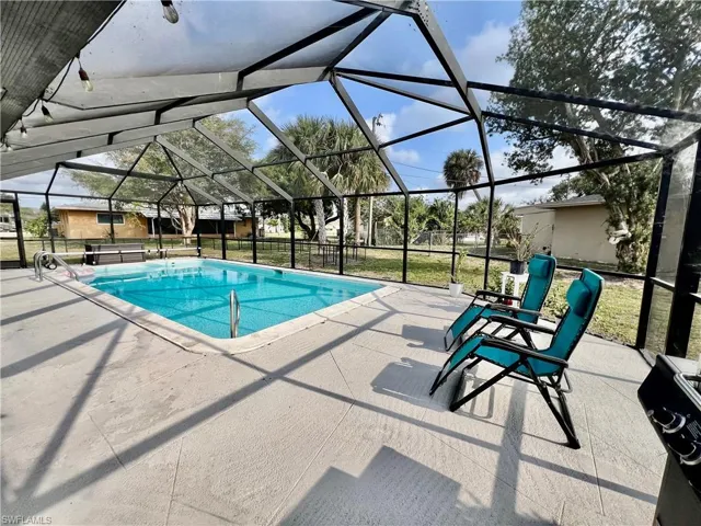 View of swimming pool featuring screen enclosure and a patio area