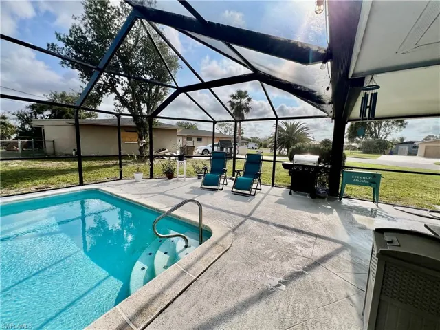 View of swimming pool featuring a yard, screen enclosure, and a patio area