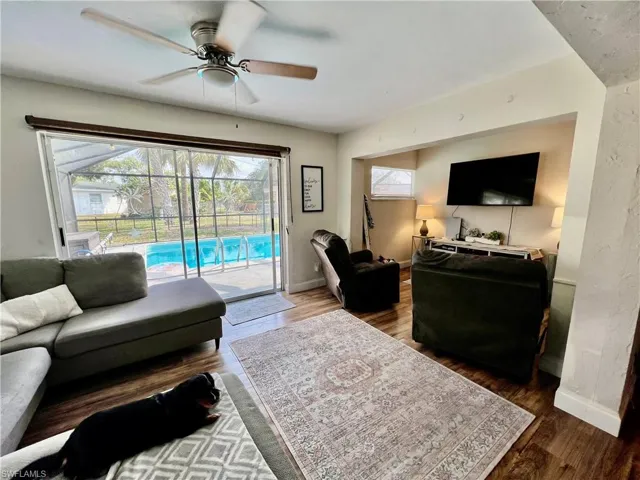Living room featuring wood-style floors and ceiling fan with access to the pool area and a healthy amount of sunlight