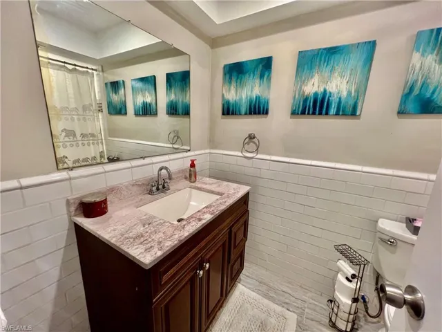 Bathroom with vanity, tile walls, and toilet.