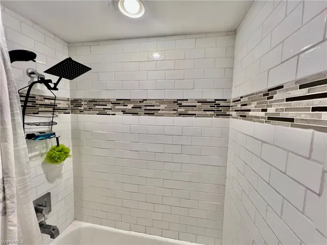 Bathroom featuring shower / tub combo with newly tiled walls and rain head shower.