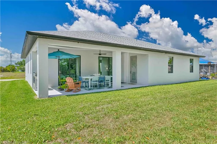 Rear view of property featuring a yard, ceiling fan, and a patio area
