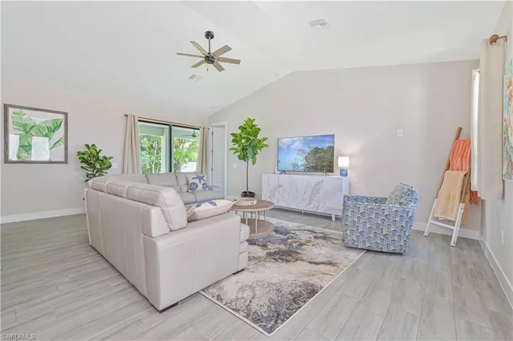 Living room with ceiling fan and lofted ceiling
