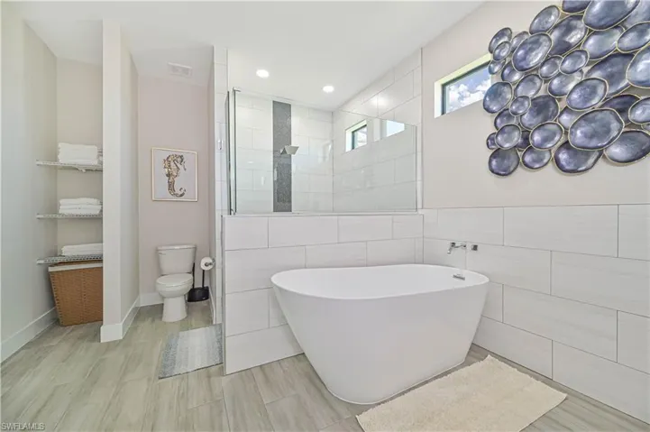 Bathroom with tile walls, tile flooring, shower with separate bathtub, and toilet