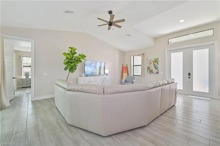Living room with ceiling fan, light hardwood / wood-style floors, french doors, and vaulted ceiling