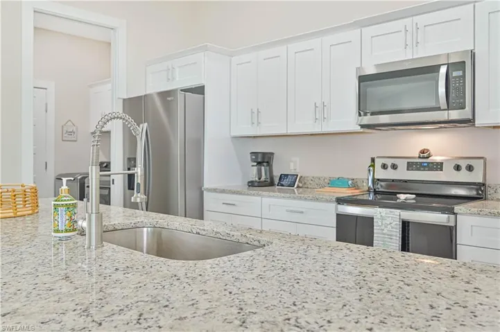 Kitchen featuring white cabinets, appliances with stainless steel finishes, and light stone countertops