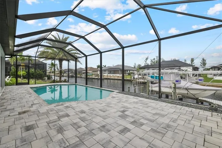 Outdoor pool featuring a water view, a boat dock, boat lift, glass enclosure, and a sunroom