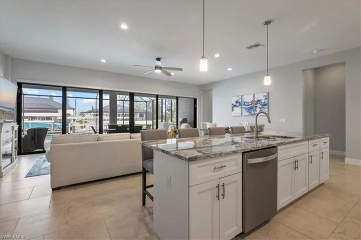 Kitchen featuring a breakfast bar area, light stone counters, decorative light fixtures, recessed lighting, and stainless steel dishwasher