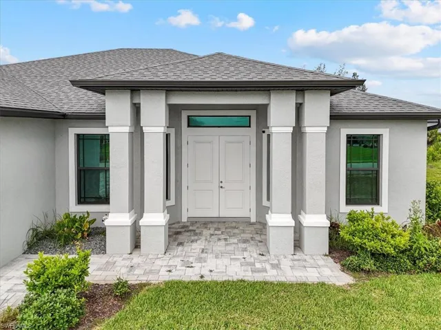 Property entrance featuring roof with shingles, stucco siding, and covered porch