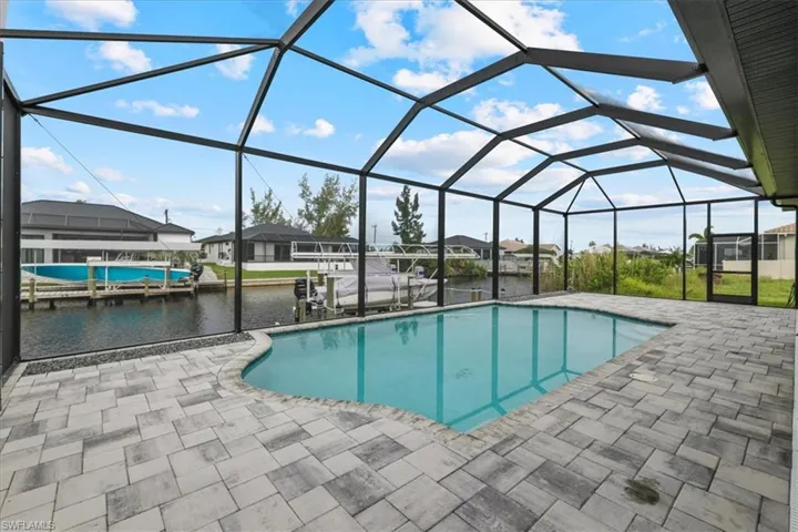 Outdoor pool featuring a sunroom, a boat dock, a patio, boat lift, and a lanai