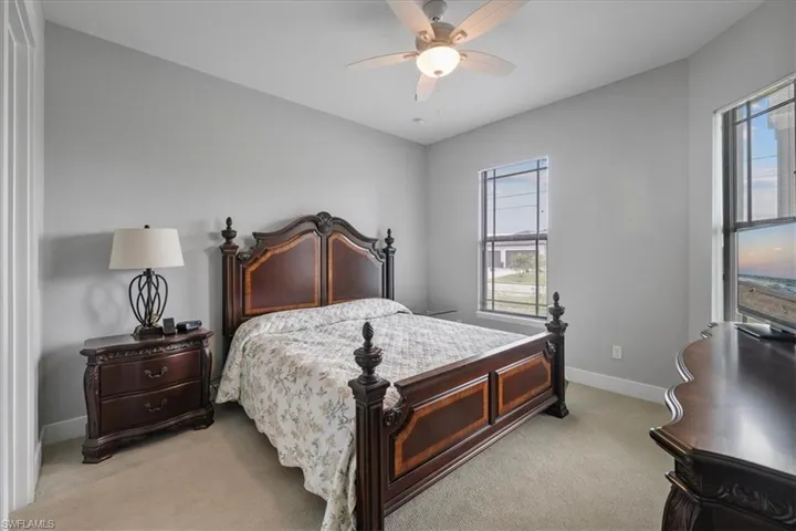 Bedroom with light colored carpet and a ceiling fan