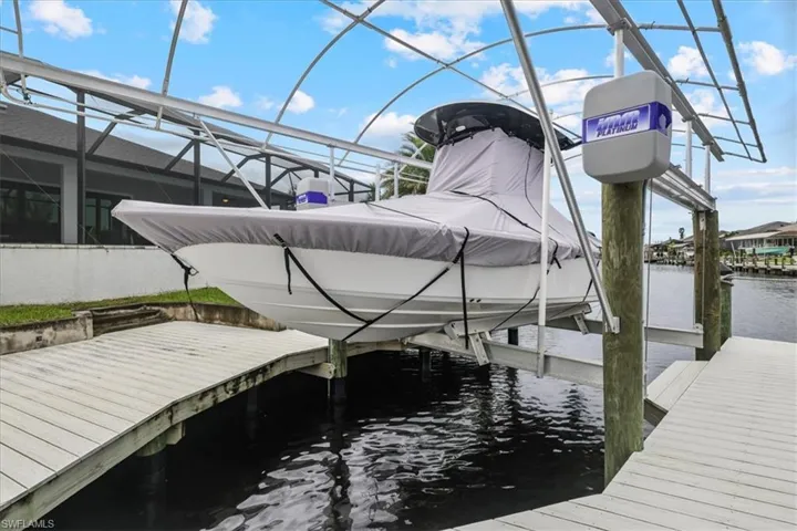 Dock area featuring boat lift, a water view, and a sunroom