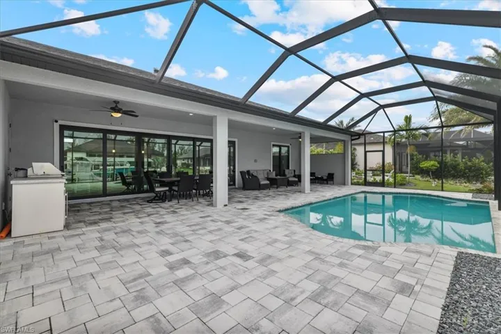 Swimming pool featuring ceiling fan, a sunroom, a patio area, glass enclosure, and an outdoor hangout area