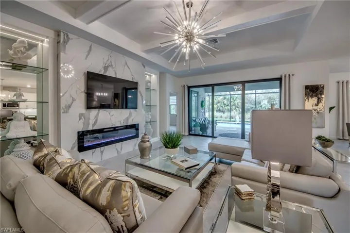 Living room with a tray ceiling, an inviting chandelier, and a high end fireplace