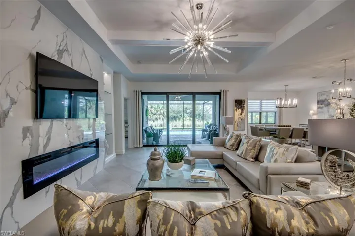 Tiled living room featuring a tray ceiling and an inviting chandelier