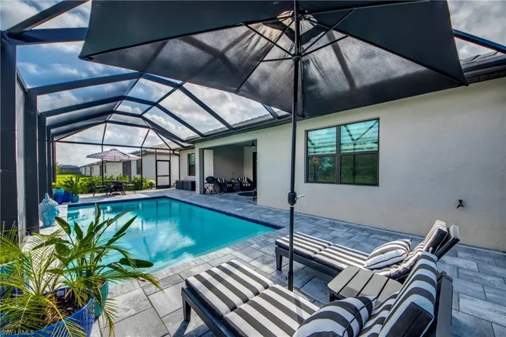 Pool featuring a ceiling fan, glass enclosure, and a patio area