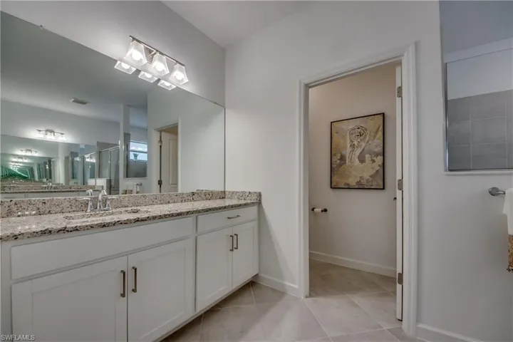 Bathroom with an enclosed shower, tile patterned flooring, and vanity