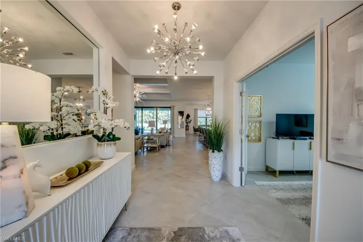 Entrance foyer with ceiling fan with notable chandelier and light tile patterned floors