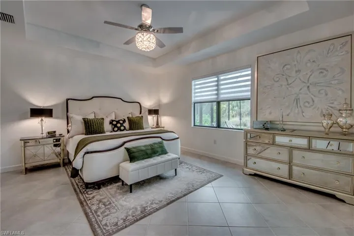 Bedroom featuring a tray ceiling, light tile patterned floors, and ceiling fan