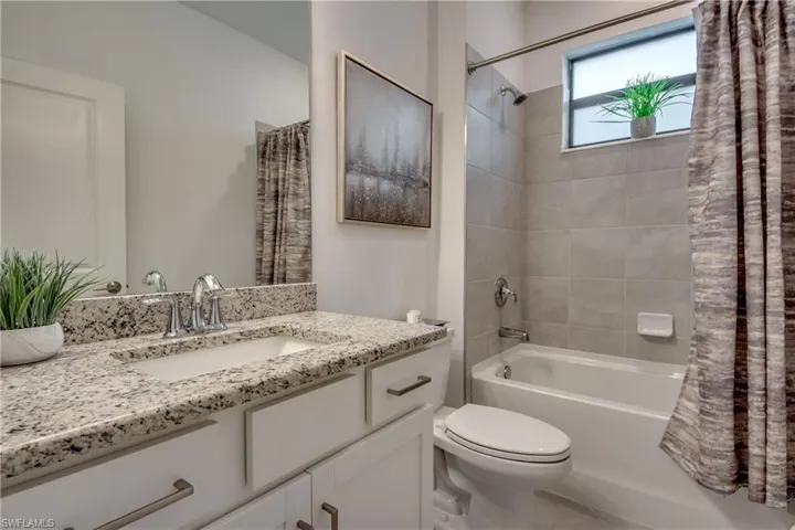 Full bathroom with shower / bathtub combination with curtain, vanity, and toilet