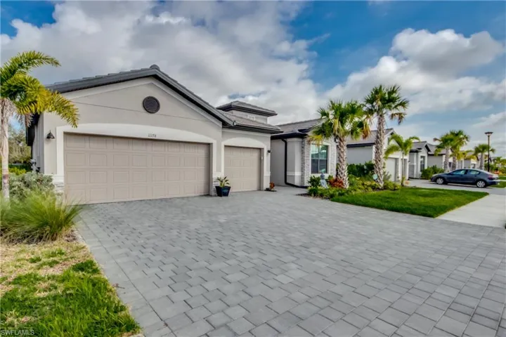 View of front facade featuring a garage, decorative driveway, and stucco siding