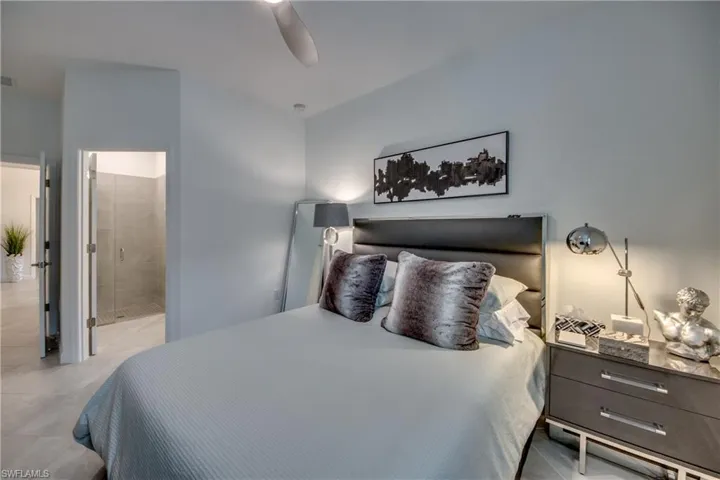 Bedroom featuring light tile patterned flooring, ceiling fan, and ensuite bath