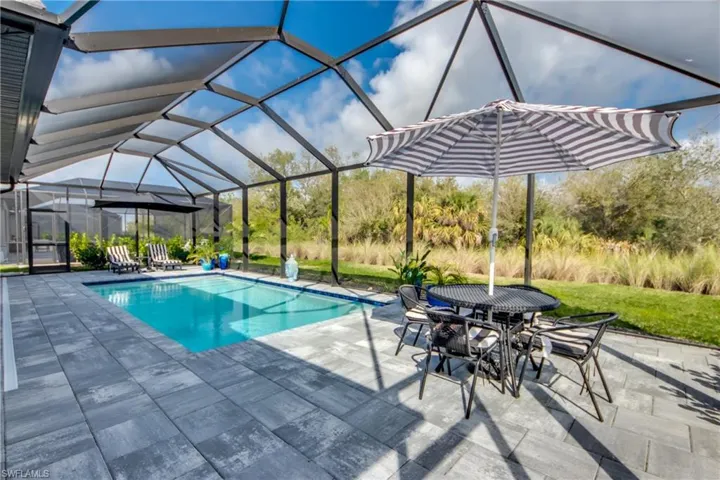 View of pool featuring glass enclosure and a patio