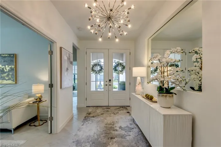 Foyer entrance with a notable chandelier, french doors, and light tile patterned floors