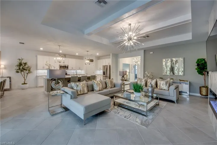 Living room with a tray ceiling, a notable chandelier, and light tile patterned floors