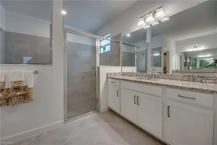Bathroom featuring tile patterned floors, vanity, and an enclosed shower
