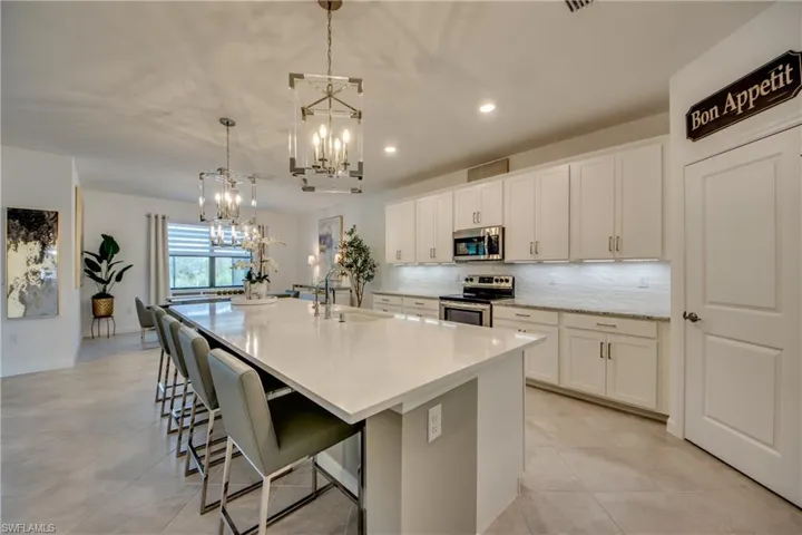 Kitchen with sink, white cabinetry, pendant lighting, a large island, and stainless steel appliances