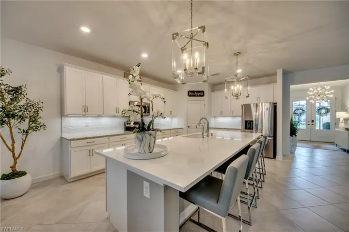 Kitchen featuring appliances with stainless steel finishes, white cabinets, pendant lighting, and a large island