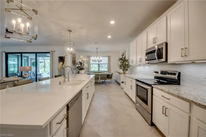 Kitchen with sink, appliances with stainless steel finishes, a kitchen island with sink, and white cabinetry
