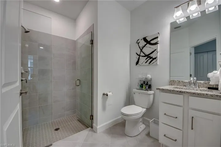 Bathroom featuring vanity, toilet, a shower with shower door, and tile patterned floors