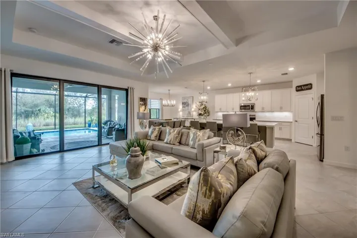 Living room with a raised ceiling, a chandelier, and light tile patterned flooring