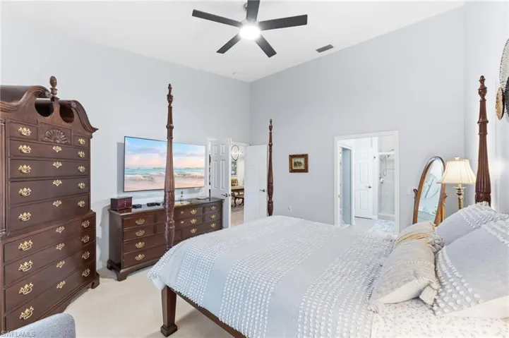 Bedroom featuring light colored carpet, a high ceiling, and a ceiling fan
