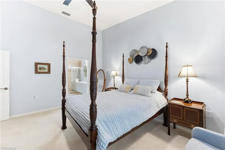 Bedroom with light carpet, a ceiling fan, and ensuite bath