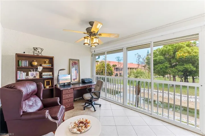 Office space featuring a textured wall, ceiling fan, and light tile patterned floors