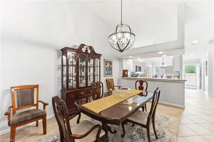 Dining space featuring suspended lighting, light tile patterned flooring, and vaulted ceiling