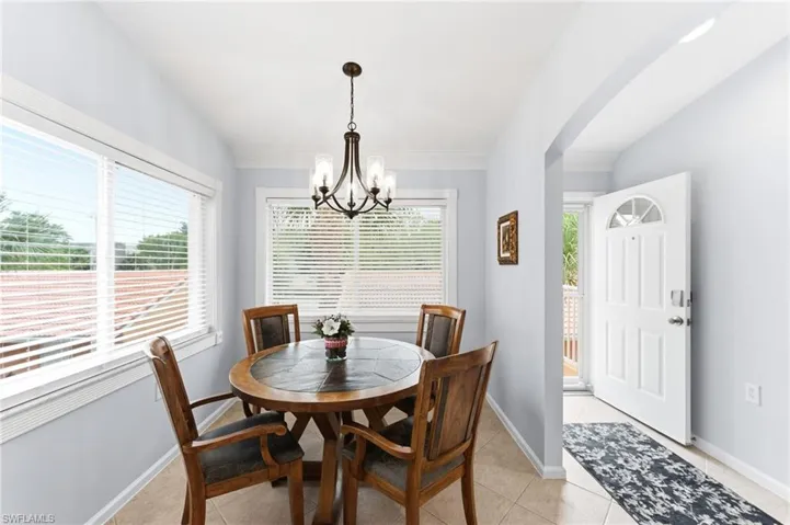 Dining area featuring vaulted ceiling, light tile patterned flooring, hanging lights, and arched walkways