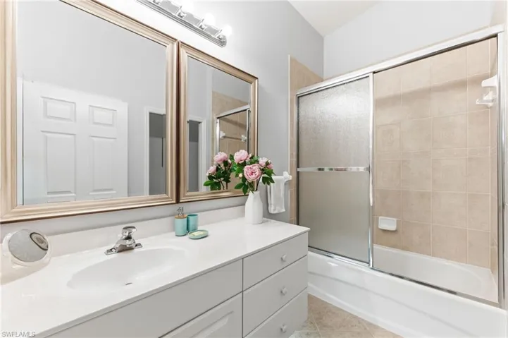 Bathroom with vanity, enclosed tub / shower combo, and light tile patterned floors