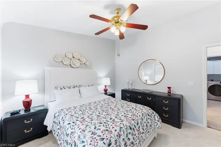 Bedroom with light carpet, washer / clothes dryer, and a ceiling fan