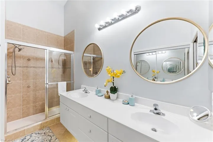 Full bathroom featuring double vanity, a shower stall, and light tile patterned floors