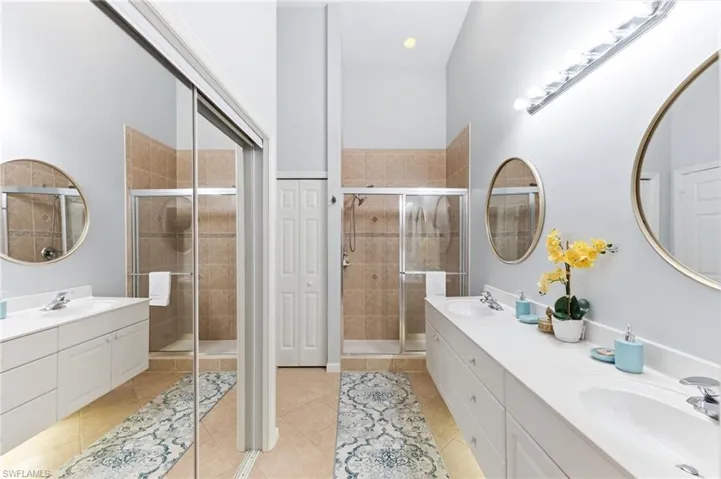 Full bathroom with double vanity, light tile patterned floors, a stall shower, recessed lighting, and a closet