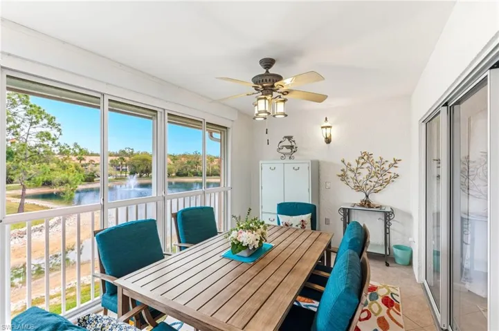 Dining space with ceiling fan, a water view, and light tile patterned floors