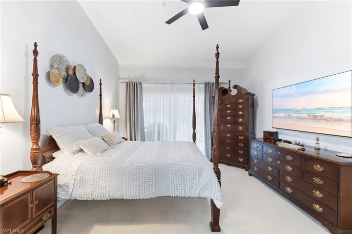 Bedroom with light colored carpet, ceiling fan, and crown molding